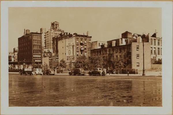 Manhattan: 6th Avenue - Minetta Street. Sixth Avenue, north from Minetta Street (right) and showing empty lots lining the east side of same. These were left when this southern extension of the Avenue was projected. The Sixth Avenue Elevated is seen making an eastward turn on West 3rd Street. In the distance appears the Empire State Building. This set of 3 views shows details of the same area., 1937-09-18